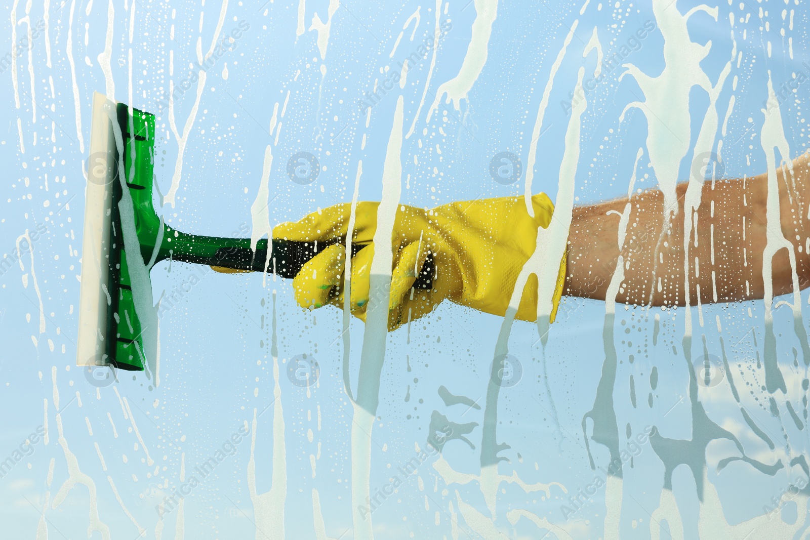 Photo of Person cleaning glass with squeegee , view from inside