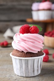 Sweet cupcake with fresh raspberries on wooden table