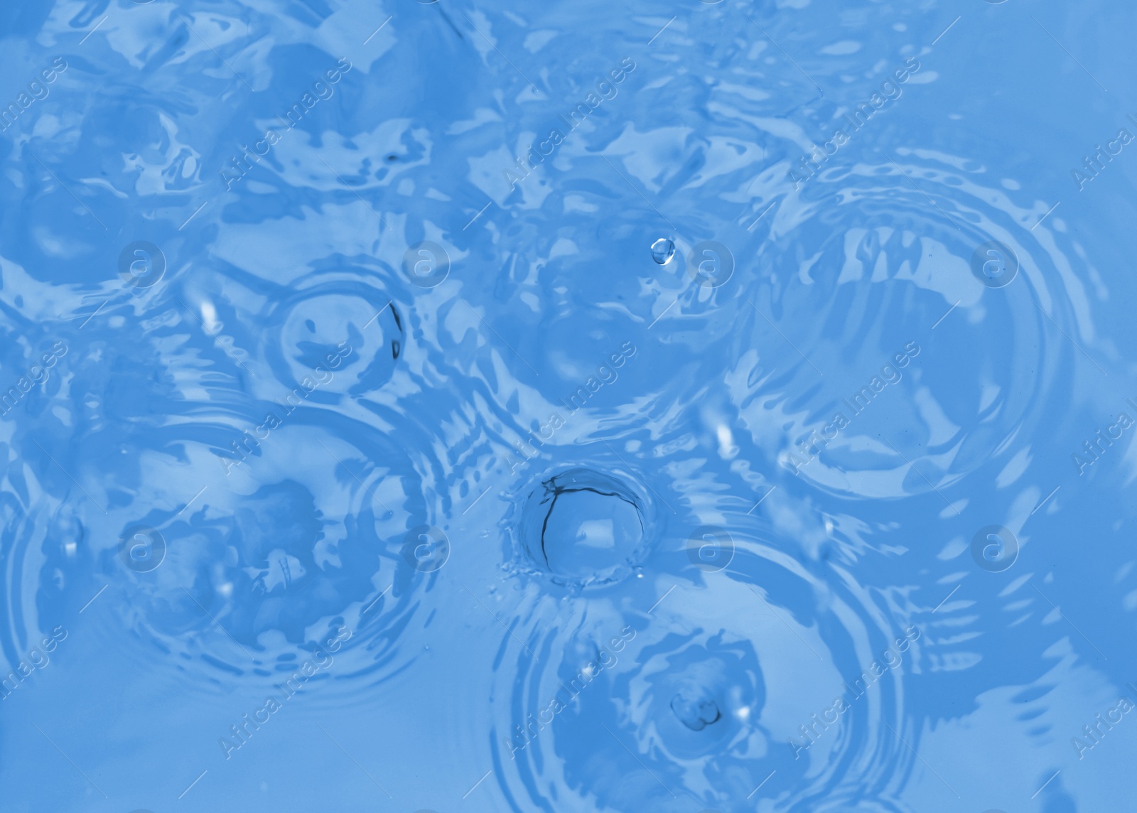 Photo of Splash of blue water with drops as background, top view