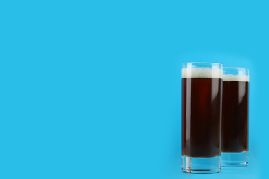 Photo of Delicious homemade kvass in glasses on light blue background. Space for text