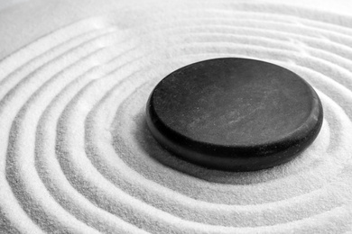 Photo of Black stone on sand with pattern. Zen, meditation, harmony
