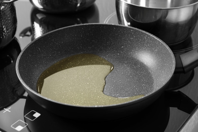 Photo of Frying pan with cooking oil on induction stove
