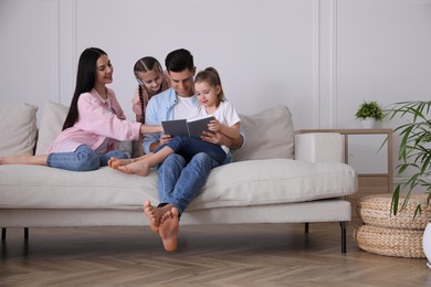Photo of Father reading book to family on sofa in living room