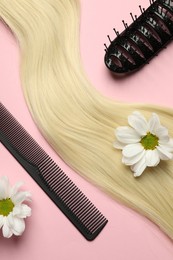 Hairdresser tools. Blonde hair lock, comb, brush and flowers on pink background, flat lay