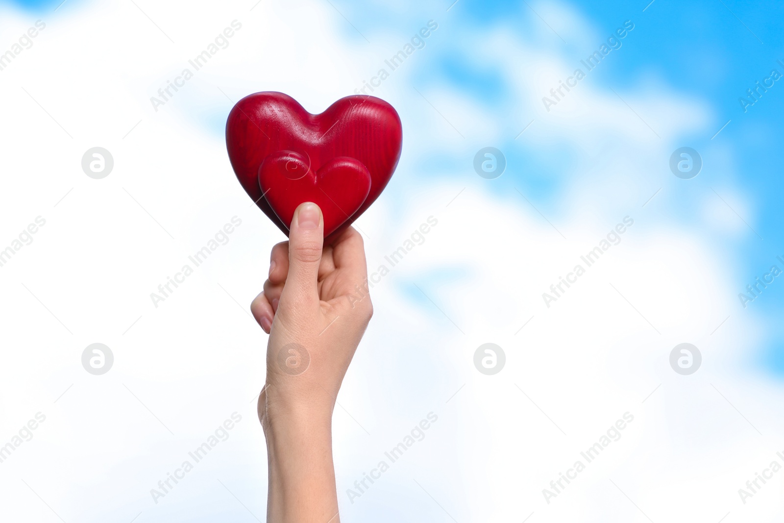 Photo of Woman holding decorative hearts in hand on color background, space for text