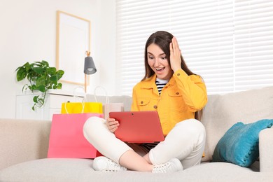 Photo of Special Promotion. Emotional woman looking at laptop on sofa indoors