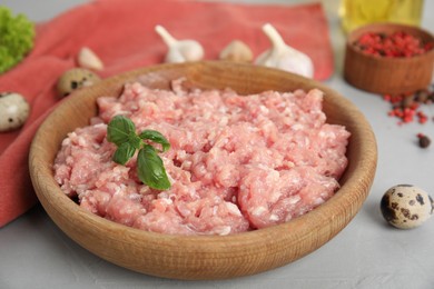 Photo of Raw chicken minced meat with basil and quail eggs on grey table, closeup