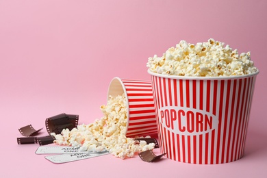 Photo of Popcorn, tickets and film footage on pink background. Cinema snack