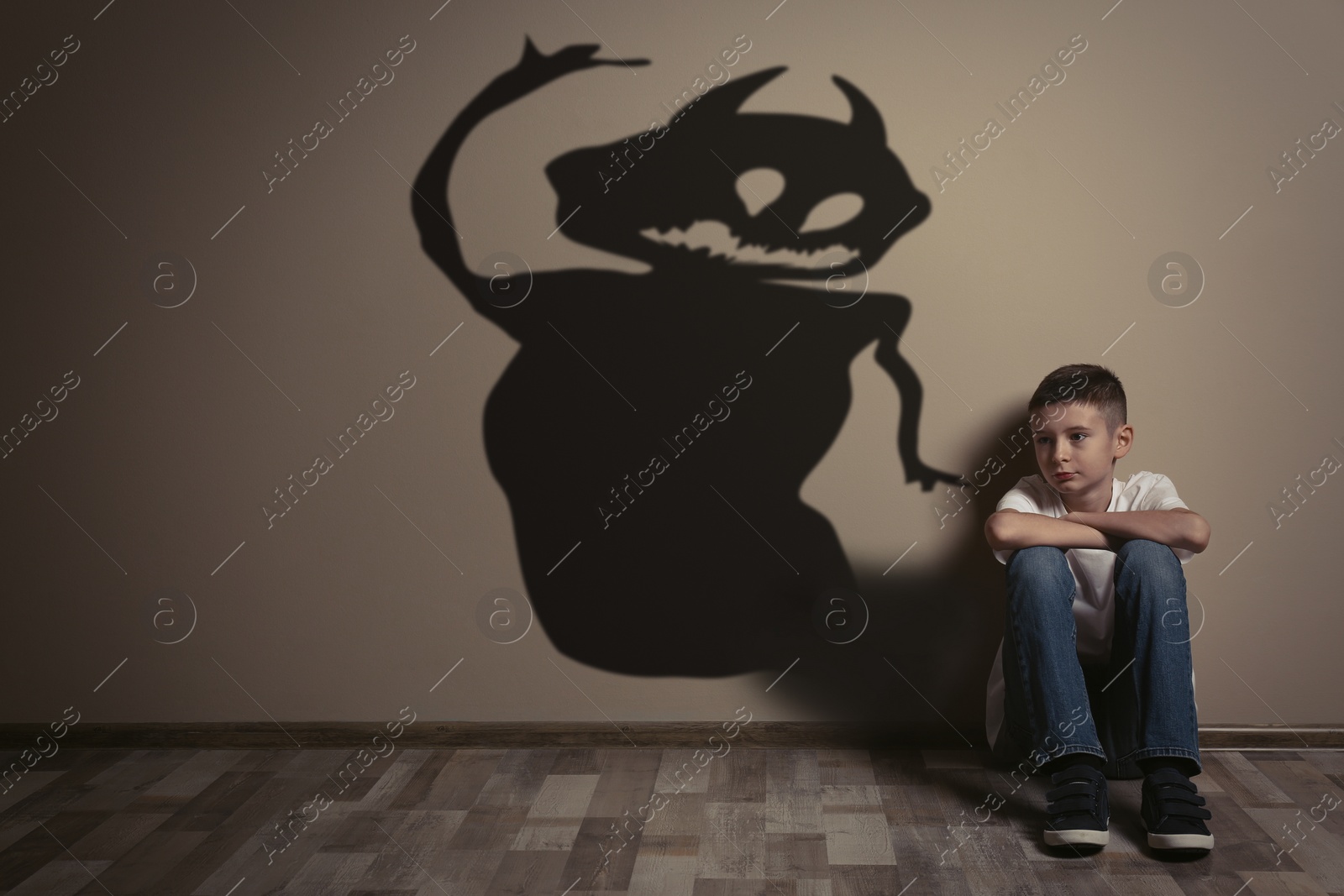 Image of Shadow of monster on wall and upset boy in room