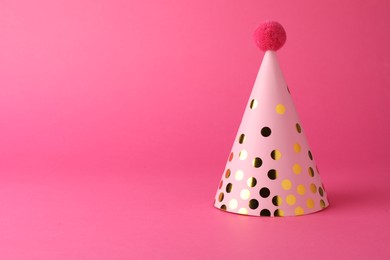 Photo of One beautiful party hat with pompom on pink background, space for text