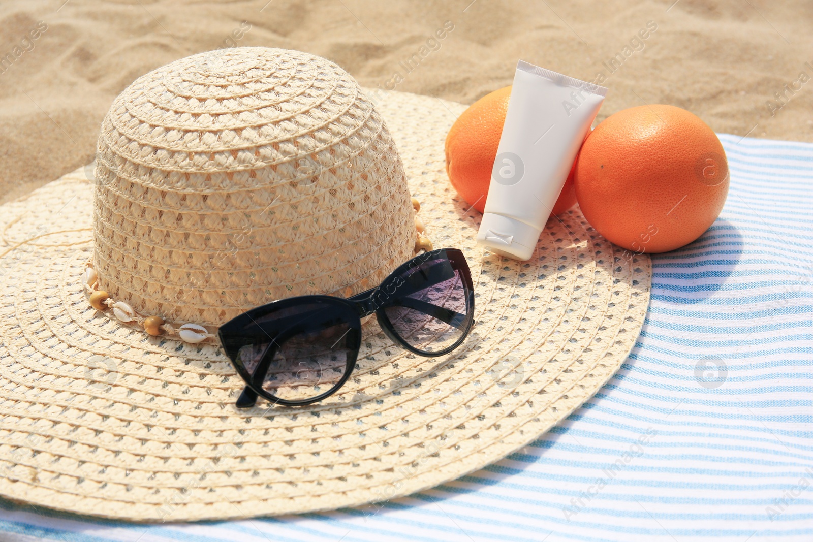 Photo of Beach accessories and oranges on sand, closeup