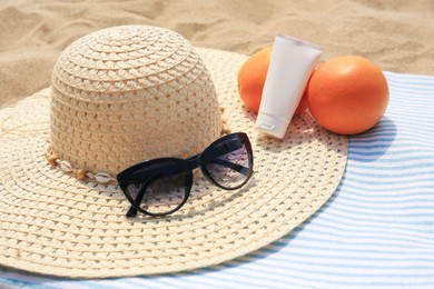 Photo of Beach accessories and oranges on sand, closeup