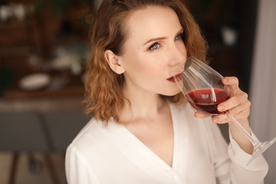 Woman with glass of delicious wine indoors