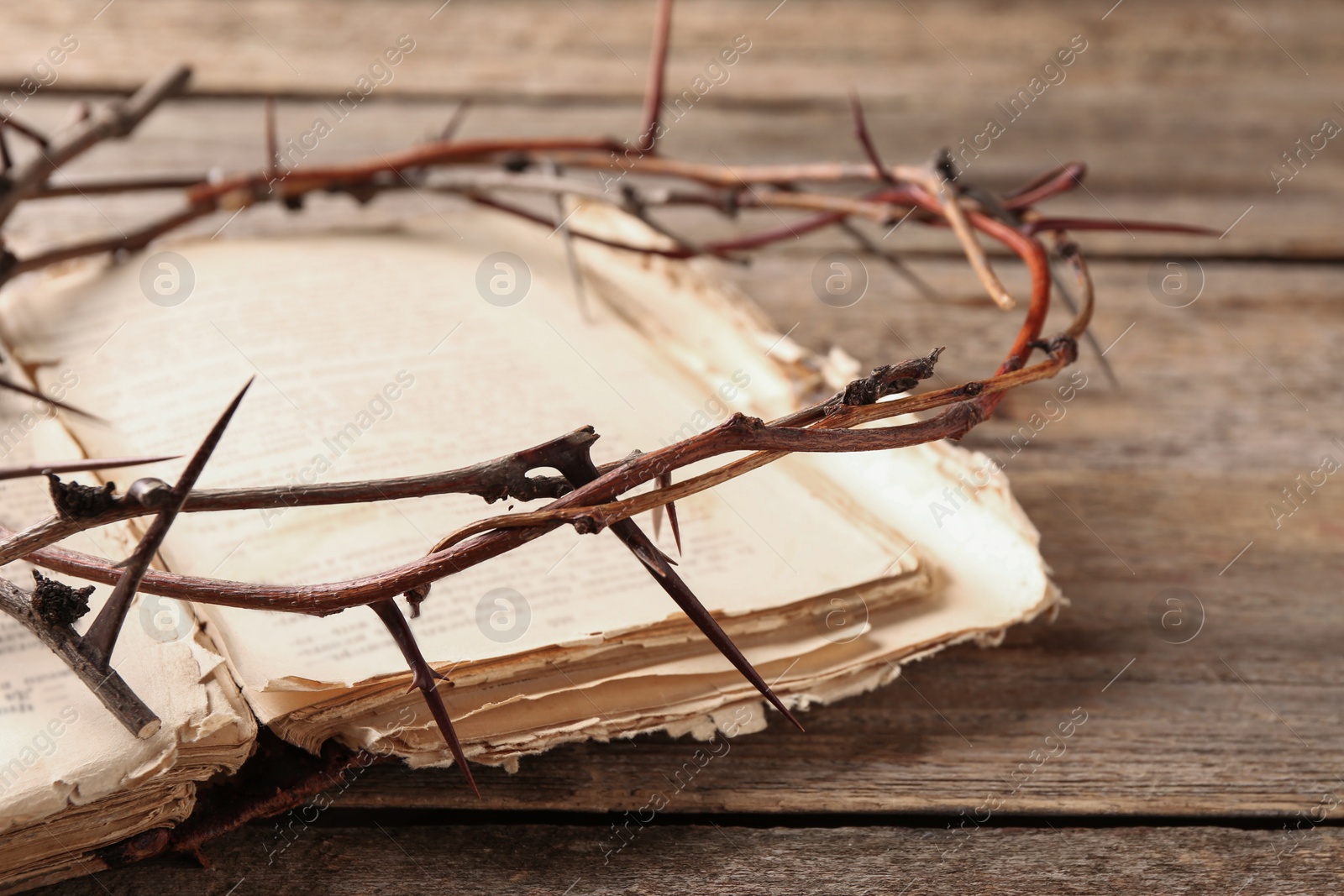 Photo of Crown of thorns and Bible on wooden table, closeup