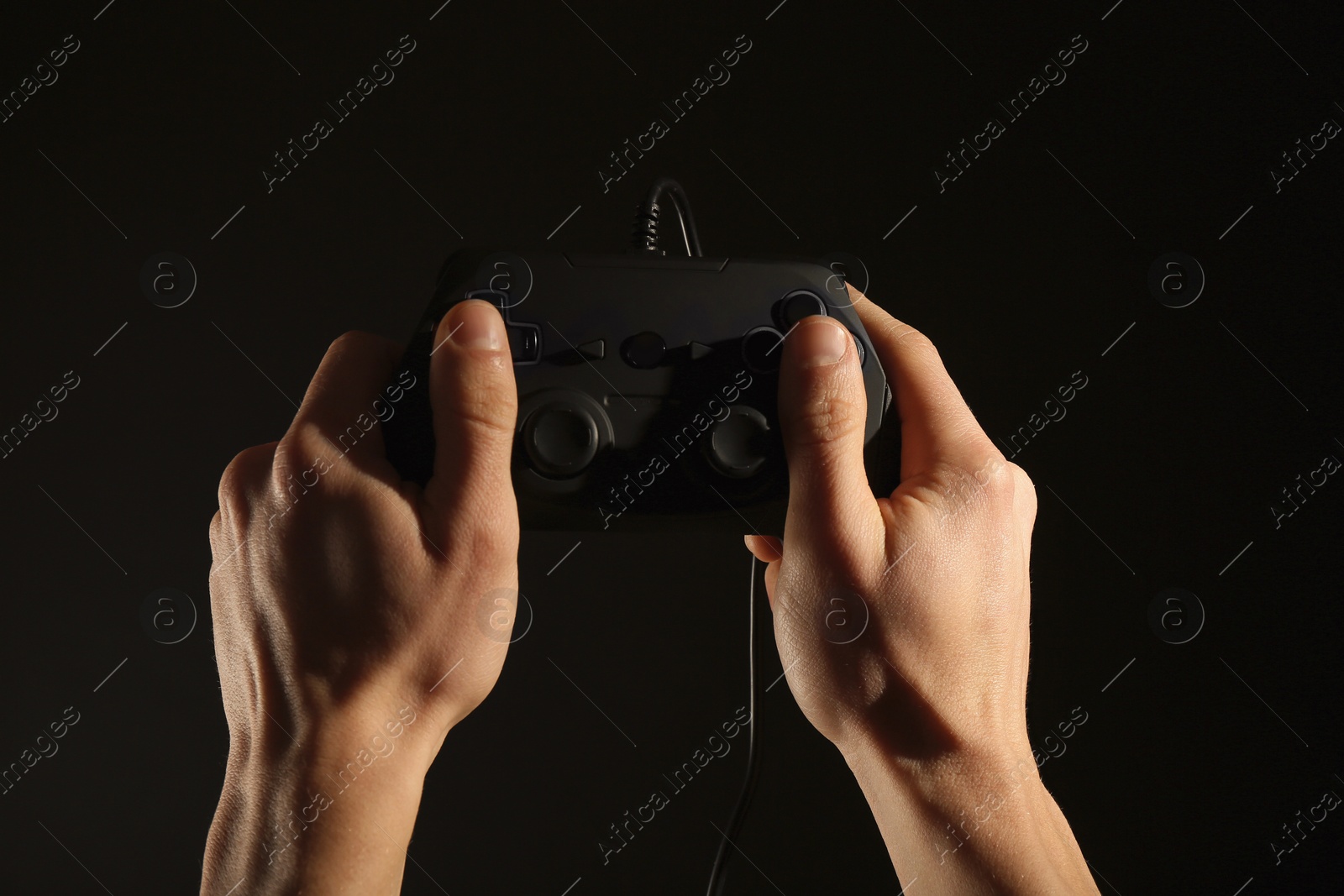 Photo of Man holding video game controller on black background, closeup