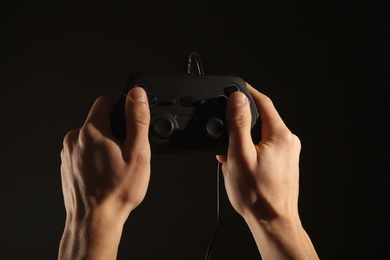 Photo of Man holding video game controller on black background, closeup