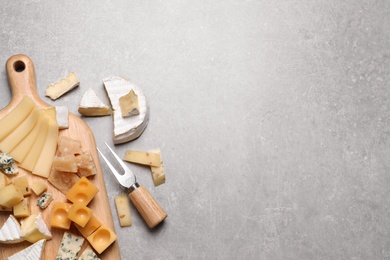 Cheese plate and cutlery on grey table, flat lay. Space for text