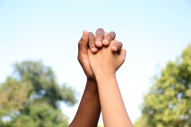 Photo of Woman and African American man holding hands outdoors, closeup