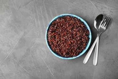 Photo of Flat lay composition with delicious cooked brown rice on grey table. Space for text