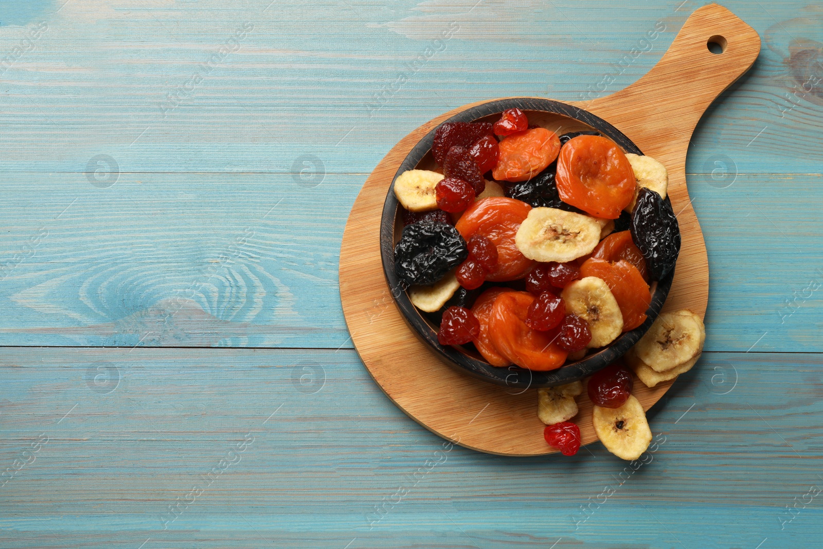 Photo of Mix of delicious dried fruits on light blue wooden table