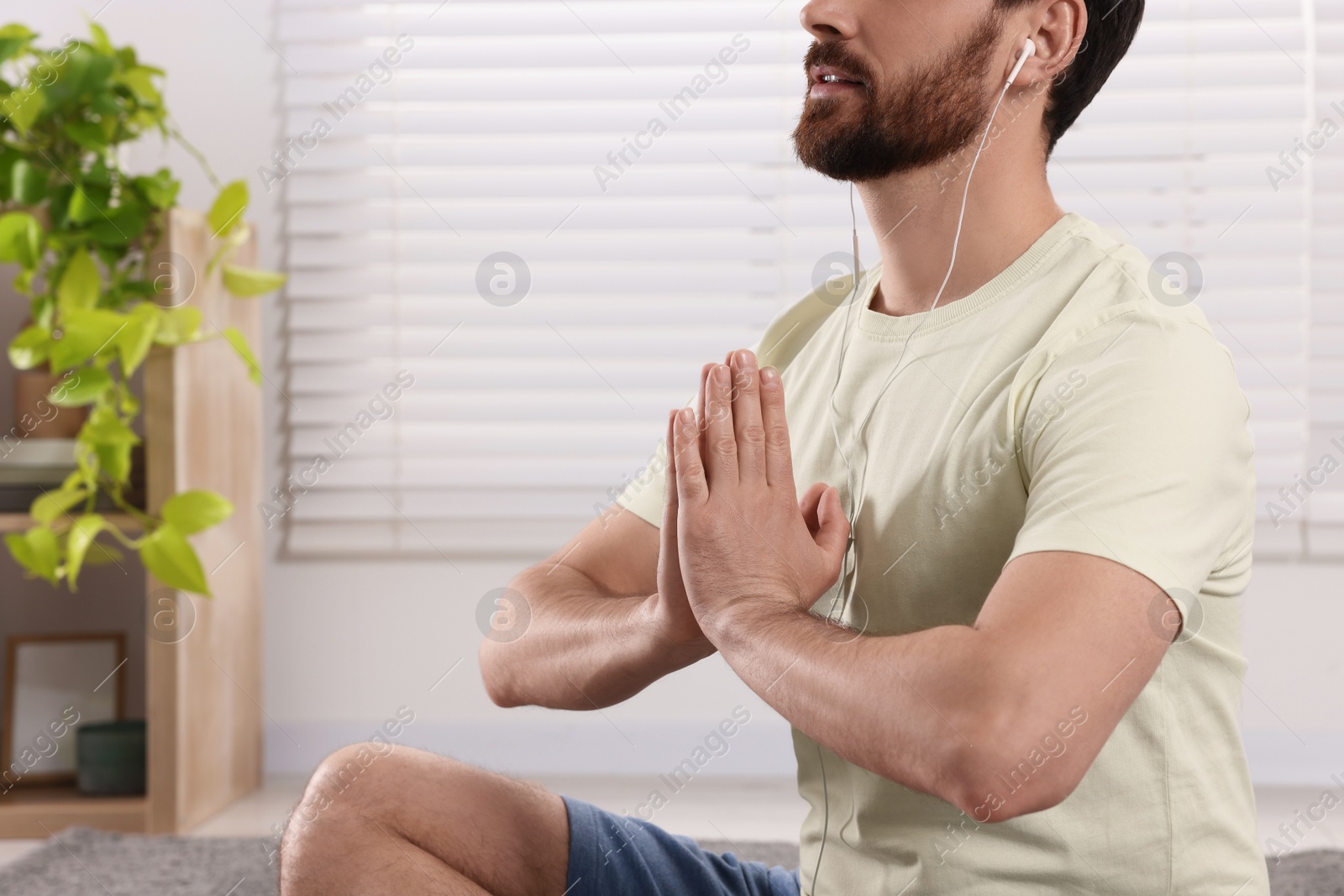 Photo of Man in earphones meditating at home, closeup. Space for text