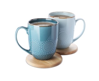 Photo of Mugs of coffee and stylish wooden cup coasters on white background