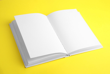 Photo of Open book with blank pages on yellow background