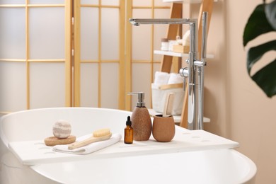 Photo of Different personal care products and accessories on bath tub in bathroom