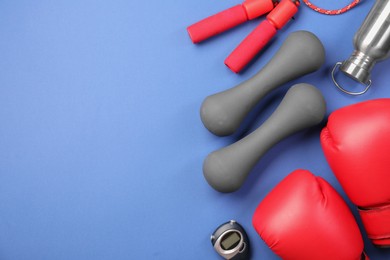 Flat lay composition with dumbbells on blue background, space for text