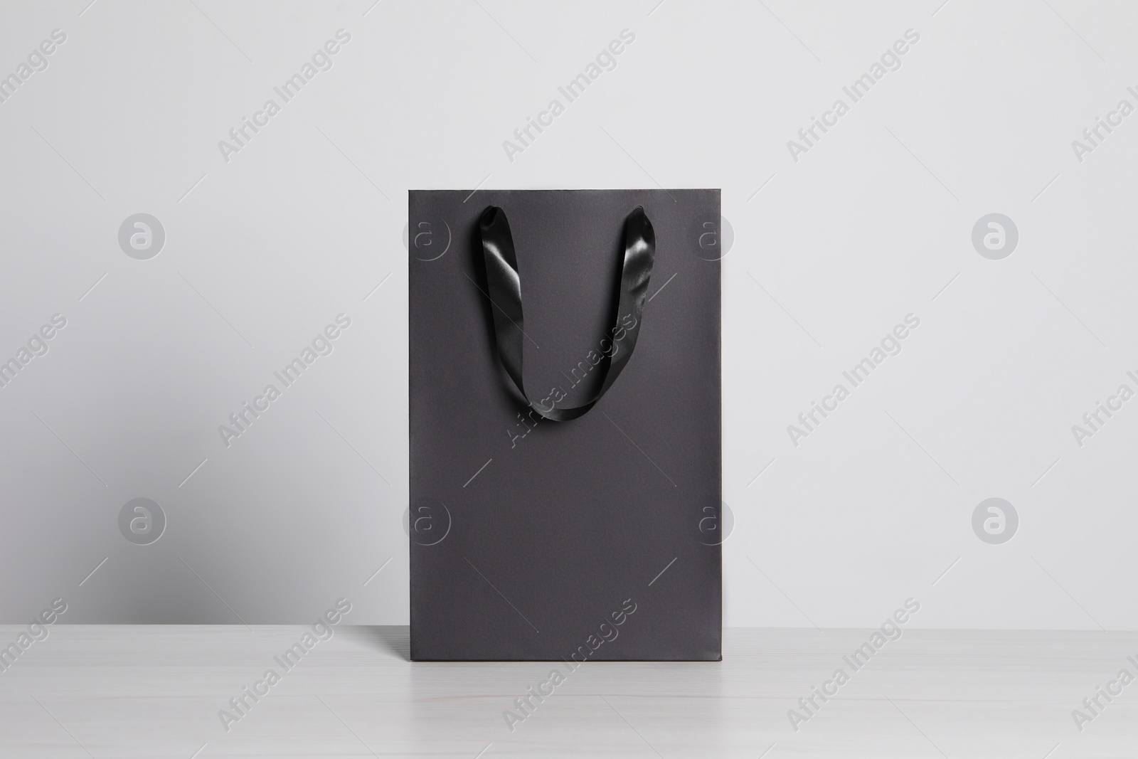 Photo of Black paper bag on white wooden table
