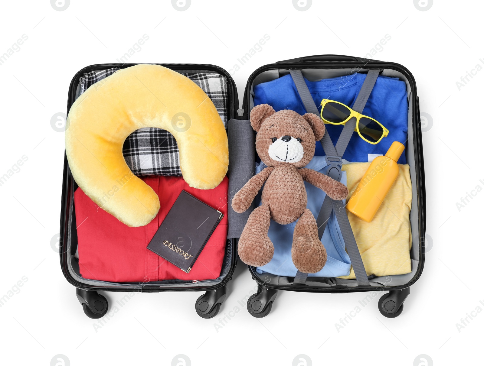 Photo of Soft travel pillow, toy bear, passport and other items in open suitcase isolated on white, top view