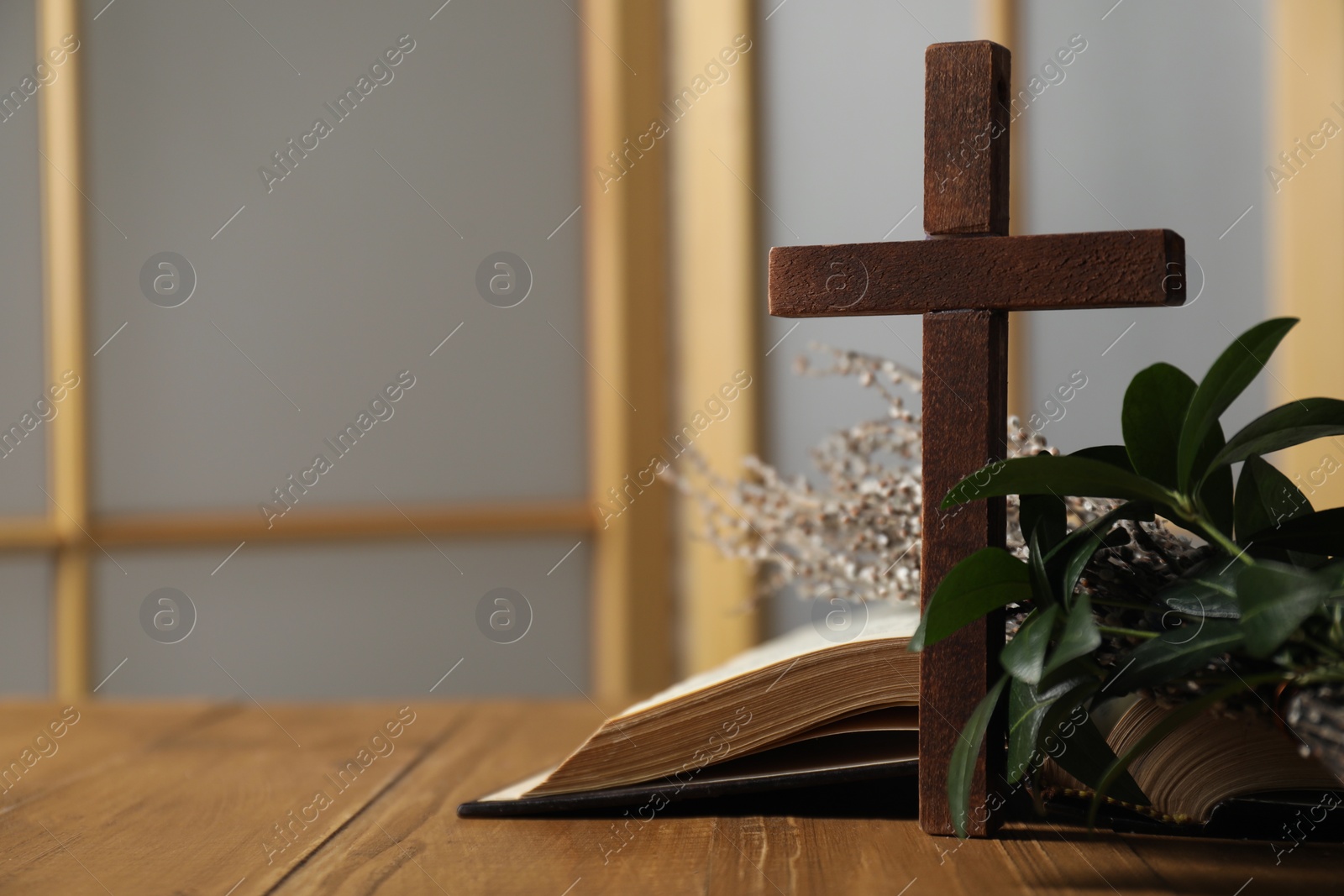 Photo of Cross, Bible and plant on wooden table, closeup. Space for text