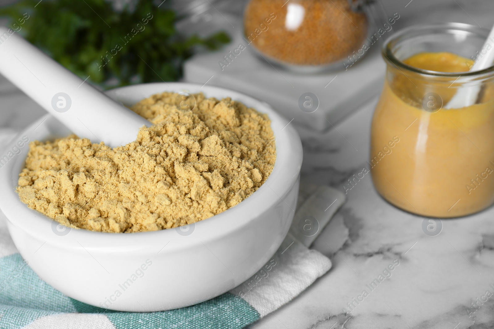 Photo of Mortar with aromatic mustard powder on white marble table, closeup