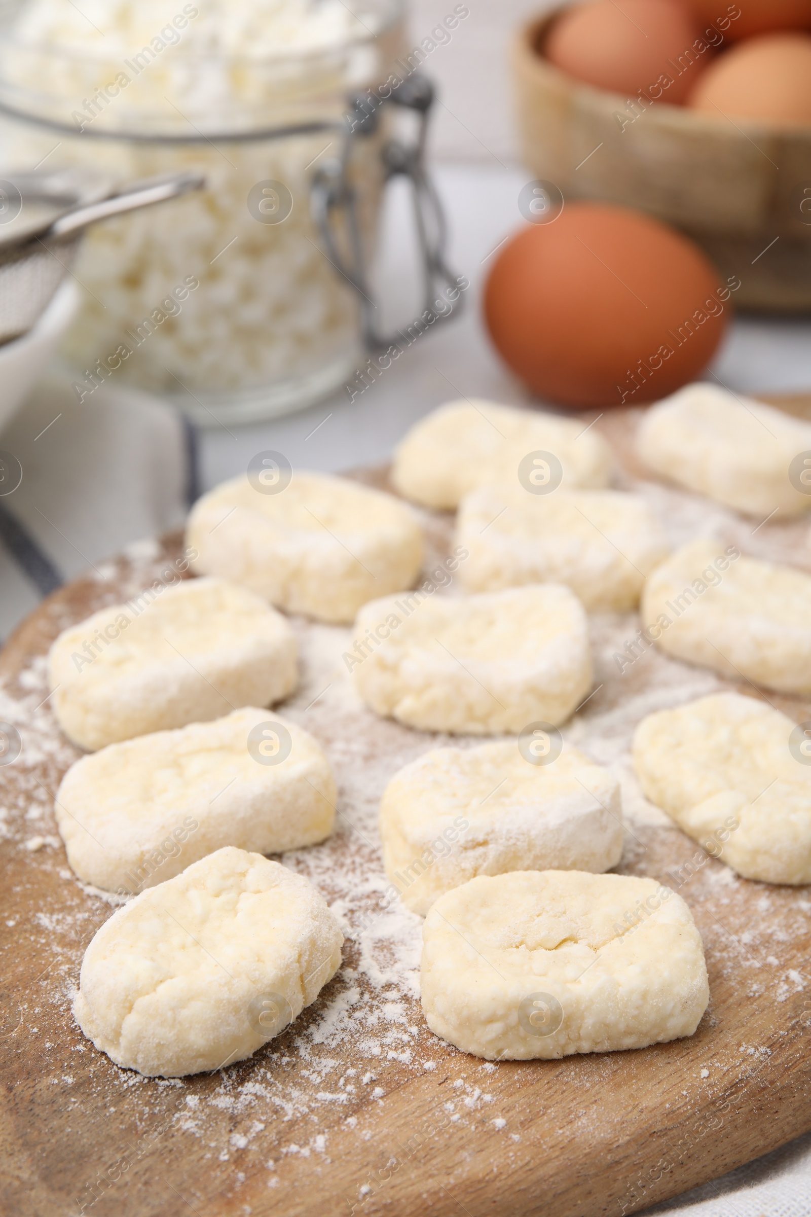 Photo of Making lazy dumplings. Wooden board with cut dough and flour on table, closeup