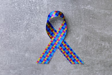 Image of World Autism Awareness Day. Colorful puzzle ribbon on light grey stone background, top view