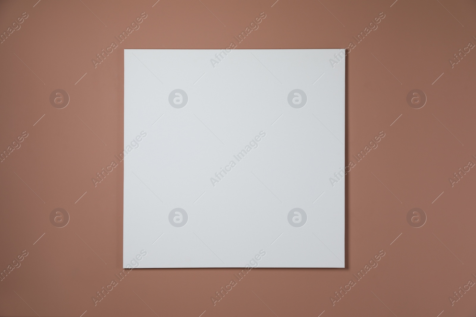Photo of Blank canvas on pale brown wall. Space for design