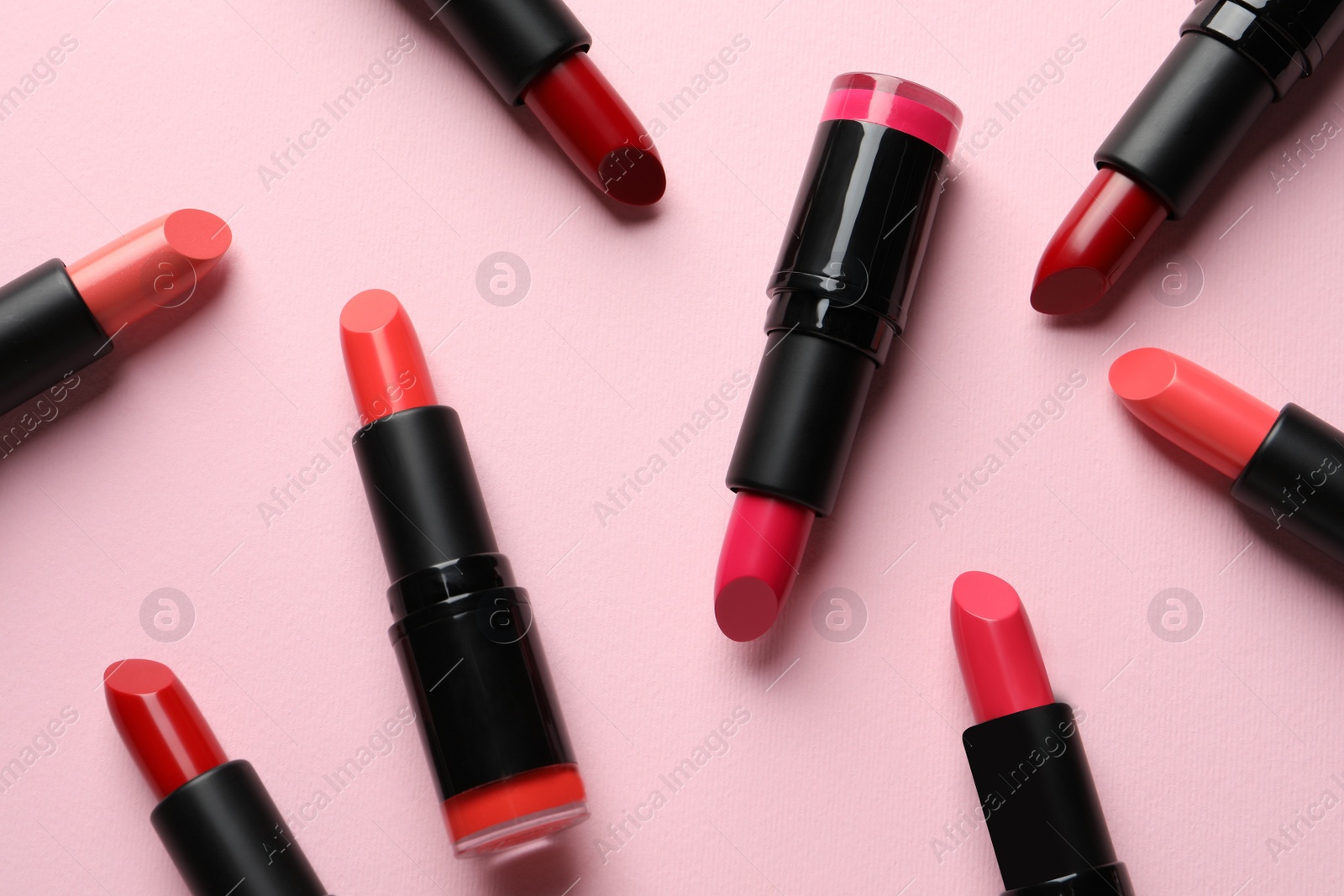 Photo of Many bright lipsticks on pink background, flat lay