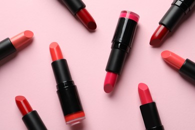 Many bright lipsticks on pink background, flat lay