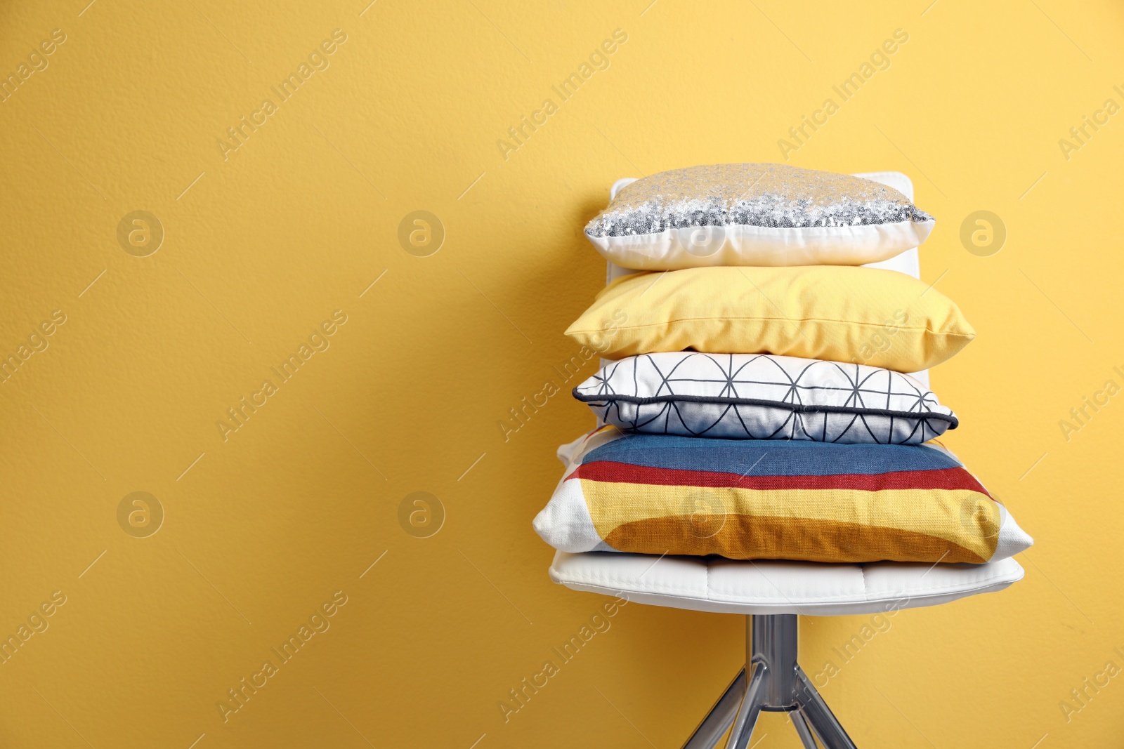 Photo of Chair with many different pillows and space for text on color background