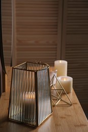 Stylish holder with burning candle on wooden table indoors