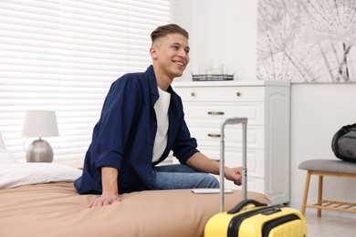 Smiling guest relaxing on bed in stylish hotel room