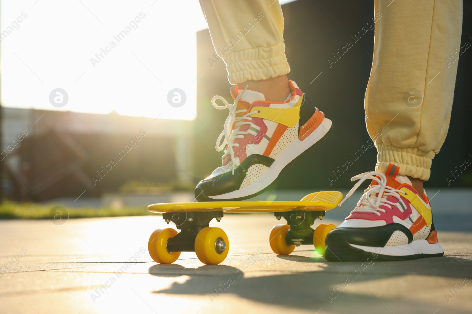 Photo of Woman with skateboard wearing stylish sneakers outdoors, closeup. Space for text