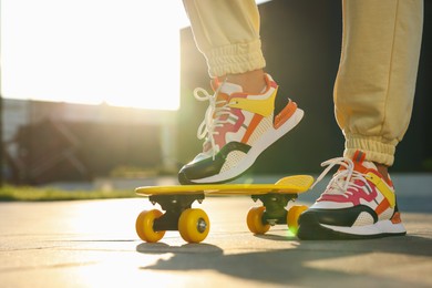 Photo of Woman with skateboard wearing stylish sneakers outdoors, closeup. Space for text