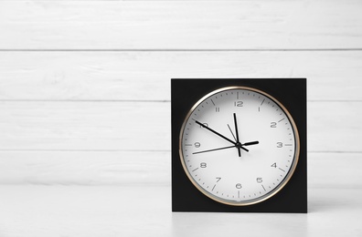 Modern clock on table against light background. Time management