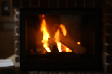 Blurred view of fireplace with burning wood indoors