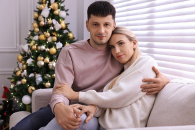 Photo of Lovely couple on sofa in room decorated for Christmas