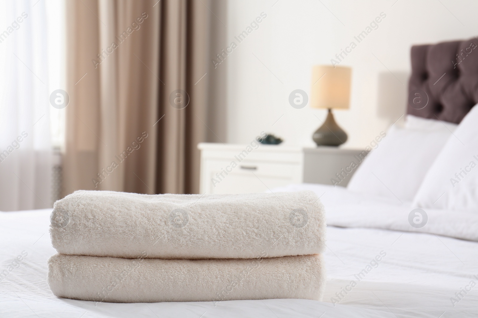 Photo of Folded soft towels on bed in room. Space for text