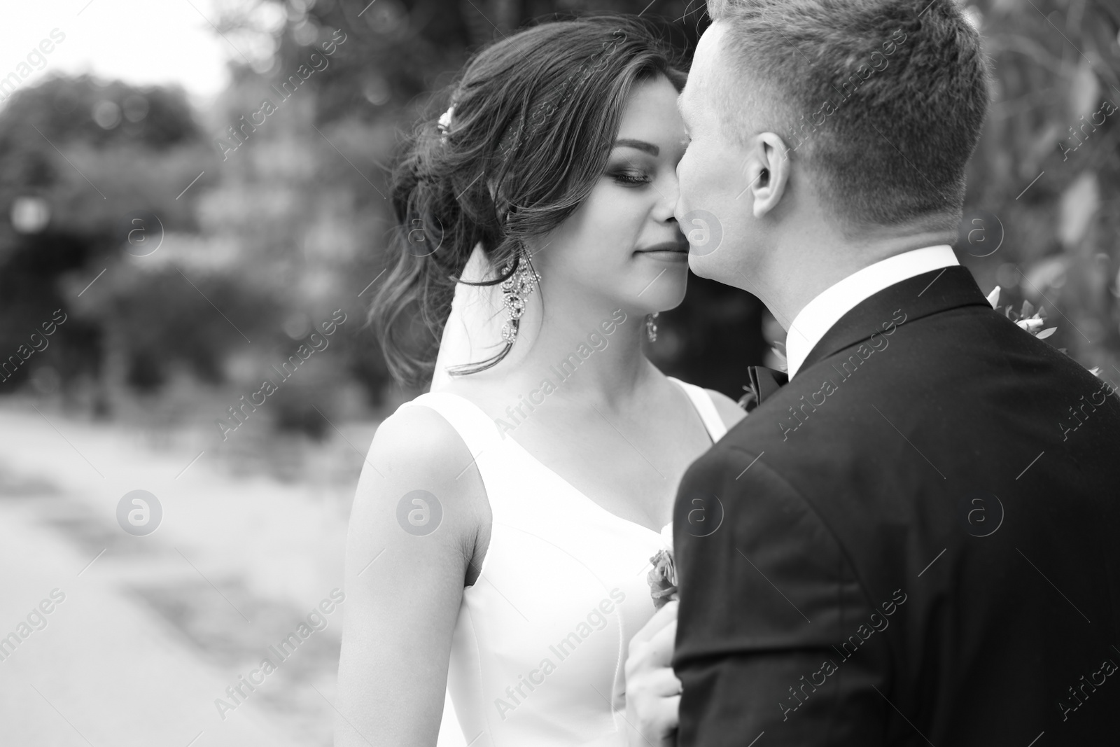 Photo of Happy newlyweds kissing outdoors, black and white effect