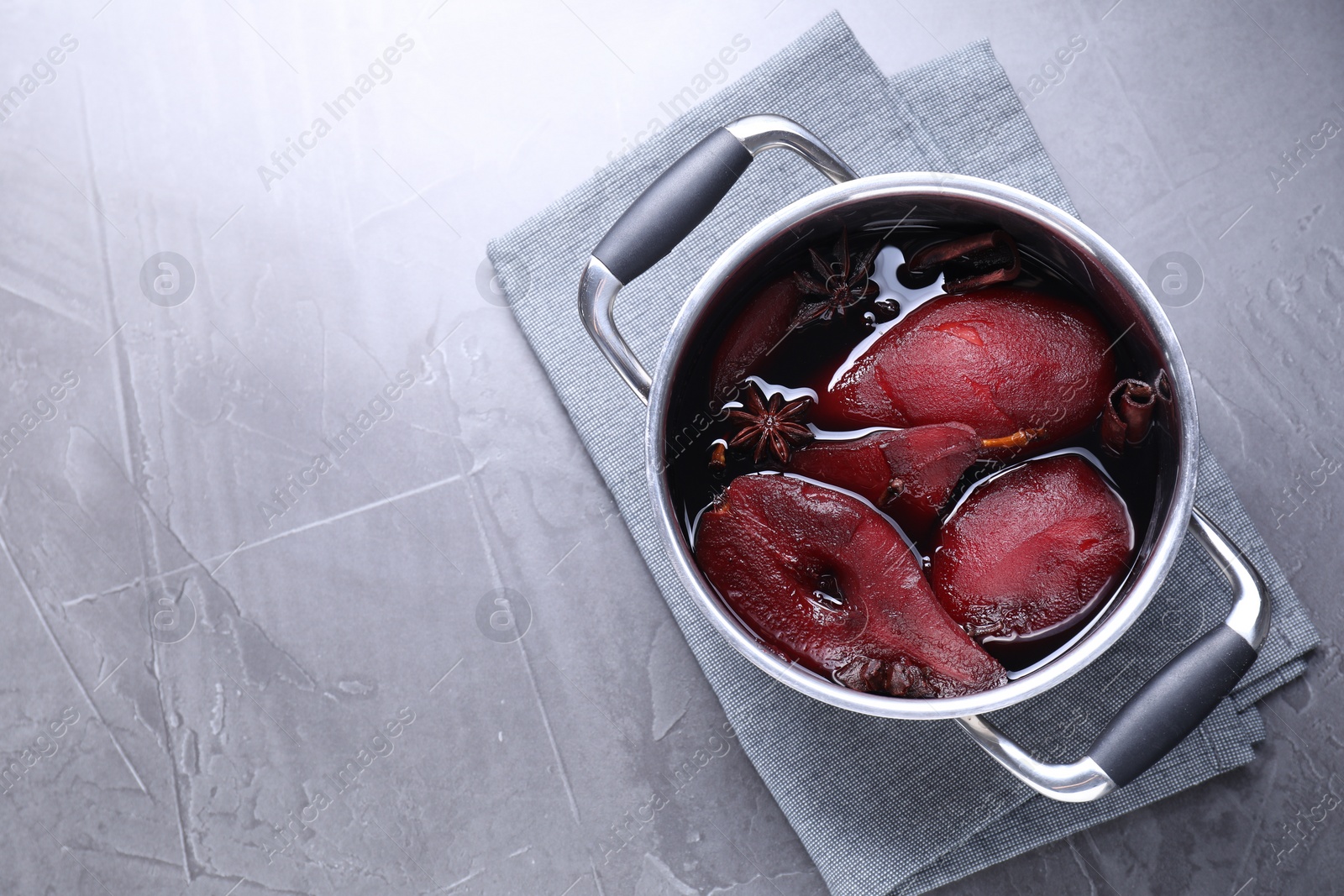 Photo of Tasty red wine poached pears and spices in pot on grey table, top view. Space for text