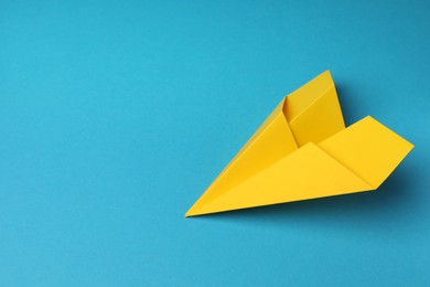 Photo of Handmade yellow paper plane on light blue background, space for text